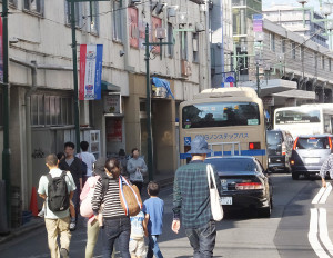 綱島駅ビル（左側）に面した道路は、綱島駅前乗り場に乗り入れる3社の路線バスが昼間でも頻繁に通り、歩道もないため、歩きづらい状況にある