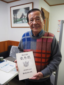 1973年に刊行された日吉台小学校の「創立100周年記念誌」を手に。亡き父・小島信作さんと清さんは卒業生。120周年では委員会を組織し「同窓会名簿」を5年もの歳月をかけて1999年に完成させた