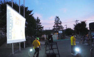 夕暮れ迫る駒林小学校に「巨大スクリーン」が登場、映画作品を“夏祭り”として上映、500人超もの人々が訪れた