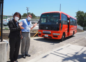 日吉自動車学校が7月1日から「新綱島線（駒岡・トレッサ経由）」の運行を開始。日吉駅便のバス前で加藤さん（右）、営業課に新たに加わった伊藤やよいさん