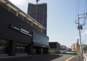 羽沢横浜国大駅前では23階建て高層マンション「リビオタワー」が来年2024年1月に完成予定。駅前再開発が進んでいる。現在一般の人が立ち入りできないエリア（中央奥）をステージやブース出展スペースとして使用する予定（4月13日）