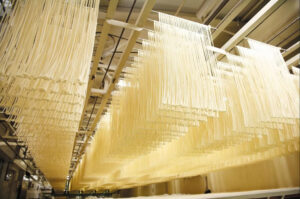 「手延べうどん」は包丁を使わずに、延ばし続けて作るため、表面はツルツル、喉越しの良さが特徴。手打ちうどんは、麺が太めで硬質な弾力を持つ力強いコシが特長である事から、両者を比較して讃岐（手打ち）の男うどん、備中（手延べ）の女うどんという言葉も生まれたとのこと。手延べ麺を作るためには、生地づくりから麺の完成までに約30時間以上かけているという（味の民芸のニュースリリースより）