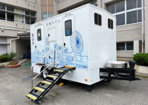 能登半島地震でも約1年間にわたり現地で使われた「トイレトレーラー」が登場。旭区の資源循環局の拠点からけん引して運ばれてくるという