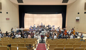 港北公会堂での練習風景。団員は現在約70人が在籍している。演奏曲目は各パートのリーダーからなる「選曲委員会」で選曲、各パートからの熱い要望などにより喧々諤々（けんけんがくがく）、舞台の大きさや予算なども考慮して、最終的に決定するという（同団提供）