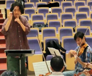 「音を抑えて」とタクトを振る松村優吾さん（練習時、同団提供）