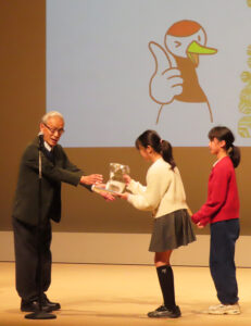 共催者のNPO法人鶴見川流域ネットワーキングの岸由二代表理事（慶應義塾大学名誉教授）から感謝状と鶴見川流域の形から生まれたキャラクター「バクちゃん」のぬいぐるみが贈られた