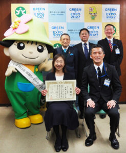 納税奨励者として表彰された宮田さんを囲んで、竹下港北区長（前列右）、小山会長、吉野仁税務課長、小松高志担当課長（後列左より）。港北区ミズキーも登場し受賞を祝った（港北区役所、1月29日）