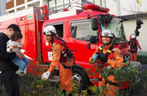 アピタテラス横浜綱島（綱島東4）で行われた「こども防災フェア」では綱島消防出張所（綱島西3）の綱島特別救助隊員が「救助演技」を披露、来訪した家族連れにも笑顔で対応していた（3月7日）
